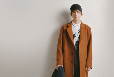  Male model wearing a white printed shirt and a brown coat from HUGO Menswear