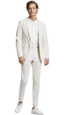 Man in tan suit, white shirt, and white sneakers by BOSS menswear