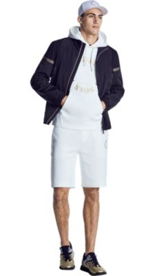 Man in white logo sweatshirt, black jacket, and white shorts in BOSS menswear