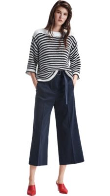 Women wearing stipped knitwear, blue trousers and orange shoes by BOSS