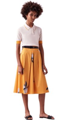 Woman wearing white knitwear, yellow skirt and black sandals by BOSS