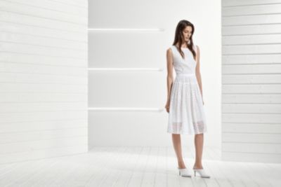 Woman is wearing white dress and mules from BOSS womenswear
