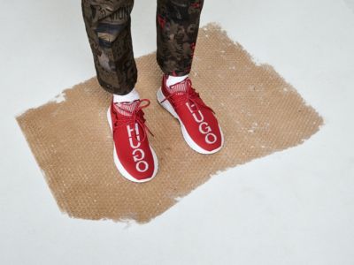 Male model wearing white socks and red sneakers with logo by HUGO