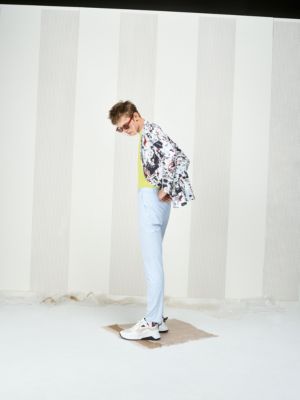 Male model wearing a jacket with print, light lime shirt, light blue trousers, white sneakers and glasses by HUGO