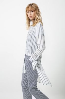 Female model wearing a white blouse with blue stripes and trousers with stripes by HUGO