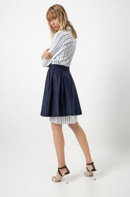 Female model wearing a white blouse with blue stripes, blue skirt and sandals by HUGO