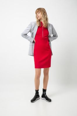 Female model wearing a grey coat, red dress and black trainers by HUGO