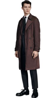 Men is wearing a brown  BOSS coat over a black BOSS suit with black BOSS neckwear and black BOSS shoes