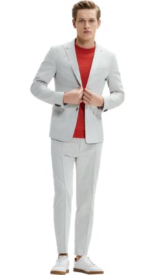 Man wearing a natural jacket, orange knitwear, natural trousers and white shoes by BOSS