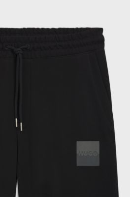 Cotton-terry tracksuit bottoms with split logo, Black