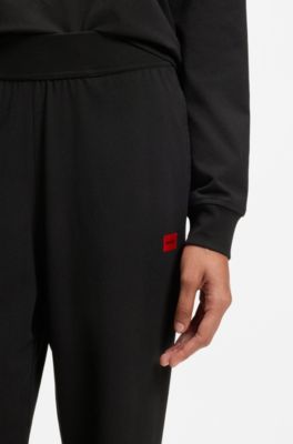 Tracksuit bottoms in stretch jersey with red logo label, Black