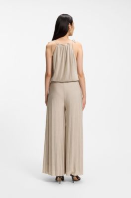 Jumpsuit med halterneck i glansig jersey med pliss&eacute;veck, Beige