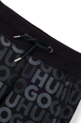 Kids' fleece tracksuit bottoms with all-over logo print, Black