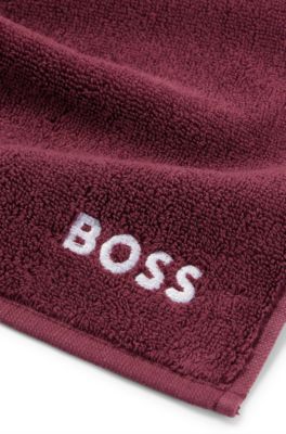 Ansiktshandduk i bomull med broderad vit logga, M&ouml;rklila