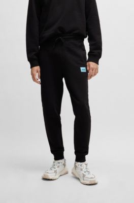 Pantalones de ch&aacute;ndal en felpa de algod&oacute;n con etiqueta con logo roja, Negro