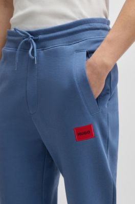 Pantalones de ch&aacute;ndal en felpa de algod&oacute;n con etiqueta con logo roja, Celeste