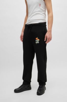Pantalones de ch&aacute;ndal relaxed fit con logo floral de dise&ntilde;o, Negro