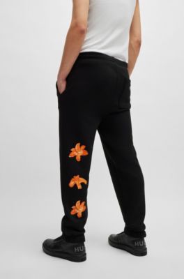 Pantalones de ch&aacute;ndal relaxed fit con logo floral de dise&ntilde;o, Negro