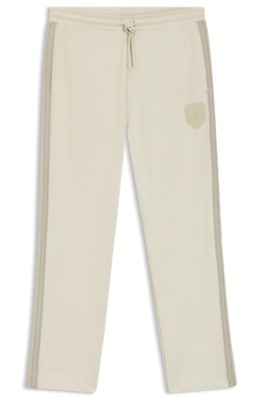 Pantalones de ch&aacute;ndal regular fit con escudo con logo, Beige claro