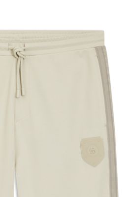 Pantalones de ch&aacute;ndal regular fit con escudo con logo, Beige claro
