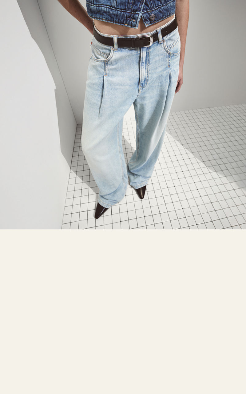 Model wearing a  slim tapered jeans trousers showing fit from back and front 