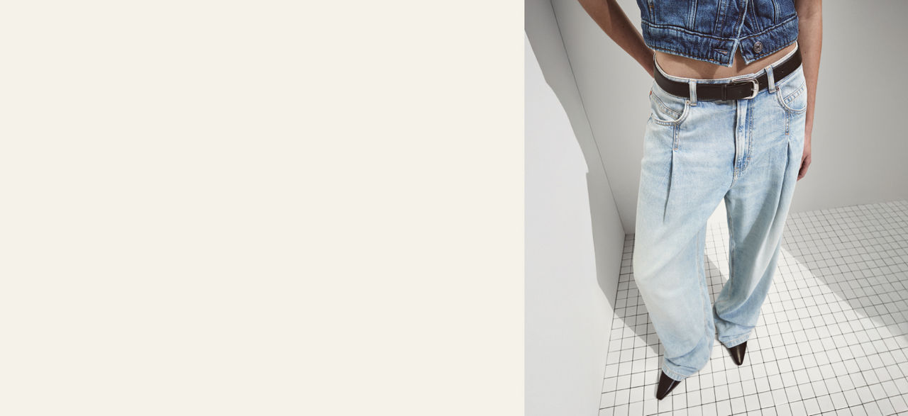 Model wearing a  slim tapered jeans trousers showing fit from back and front 