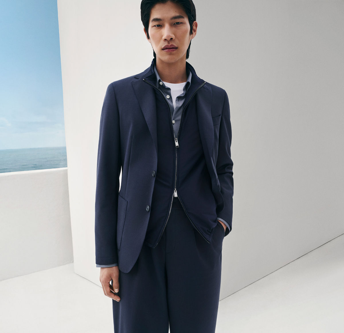 male model wearing the BOSS Performance knitted Jacket, a light jacket and matching trousers all in navy blue..