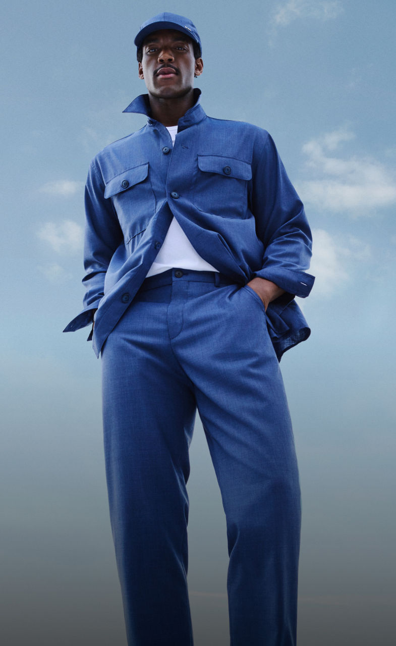 青空を背景にBOSSパフォーマンスの軽量スーツを身に着けた男性モデル