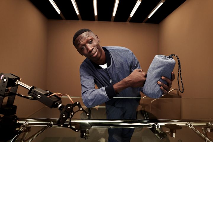 Khaby wearing the packable suit from the new performance capsule and presenting the bag 