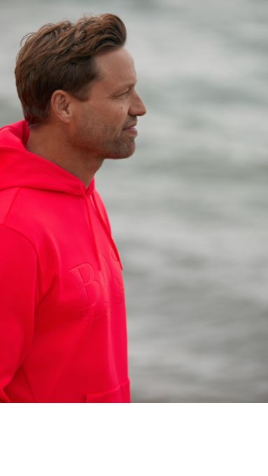 Alex Thomson draagt een neonroze trui van BOSS